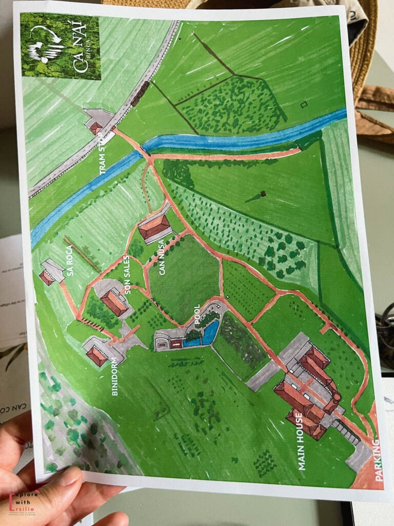 Illustrated property map of Finca Can N'ai showing the layout of buildings, pool, paths and grounds, with a blue stream running through the estate and various accommodations labeled including the main house, Sa Roca, Son Sales, and pool area