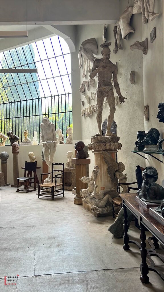 Sculpture gallery in Château de la Napoule featuring numerous busts, statues and figurines on pedestals and wall displays, with natural light filtering through a large arched window, showcasing the artistic legacy of Henry Clews Jr.